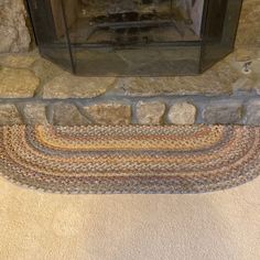 a fire place sitting next to a stone wall with a rug on the floor in front of it