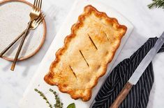 a pie on a cutting board next to a knife and fork