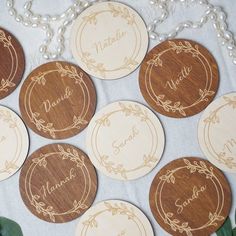 six personalized wooden coasters on a table with pearls and greenery around them