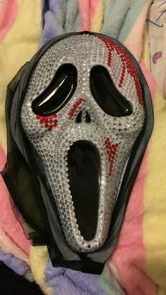 a black mask with red and white designs on it sitting on a bed covered in blankets