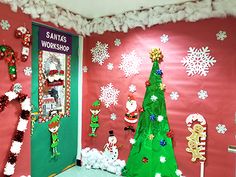 christmas decorations are displayed on the wall in front of an open door with santa's workshop written on it