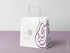 a white shopping bag with an arabic calligraphy on the front and purple lettering on the back