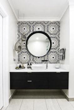 a black and white bathroom with a round mirror on the wall above the sink,