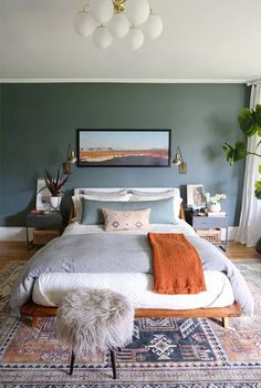 a bedroom with a bed, rugs and paintings on the wall in front of it