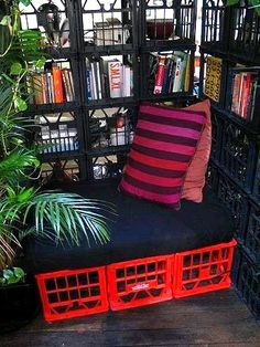 a bench made out of crates with bookshelves and plants in the back ground