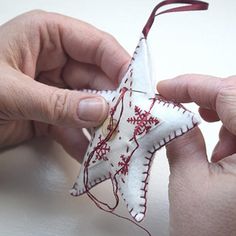 two hands are working on an ornament that looks like a christmas tree star