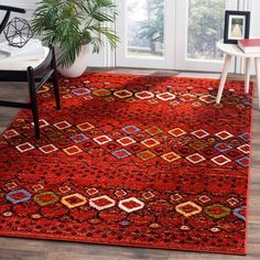 an orange area rug with geometric designs on the bottom and sides, in front of a window