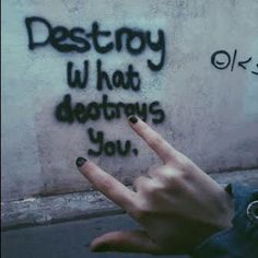 someone pointing their finger at the wall with writing on it that says destroy what detrys you