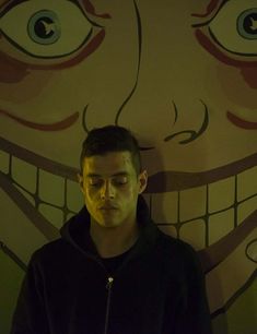 a man standing in front of a wall with an evil face painted on it