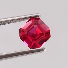 a close up of a red diamond on a white surface with two metal bars in the foreground