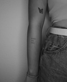 a black and white photo of a woman's arm with a butterfly on it