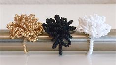 three different types of beaded flowers sitting on a metal bar with white and black beads