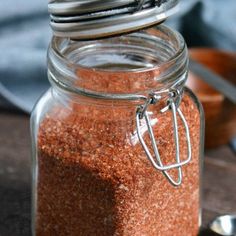 a glass jar filled with red sand next to spoons