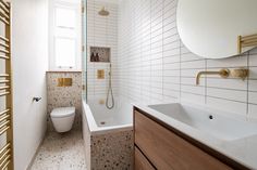 a bathroom with a sink, toilet and bathtub next to a mirror on the wall