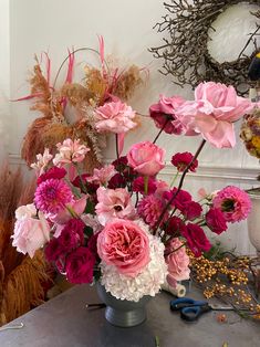 a vase filled with pink and white flowers on top of a table next to wreaths