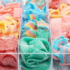 several different colors of powdered sugar in plastic bins with lids and handles on them