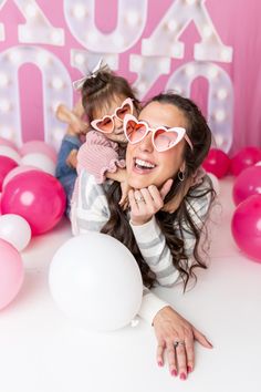 a woman holding a child in her arms while laying on the floor next to balloons