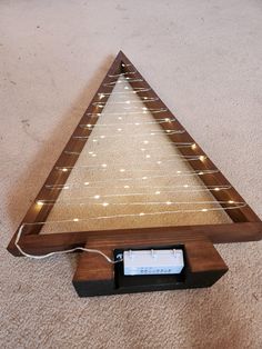 an electronic device is connected to a wooden triangle with string lights on the bottom and sides