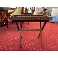 an old wooden table sitting on top of a red carpet