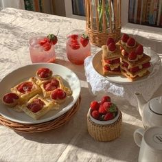 strawberries are on top of waffles next to cups and teapots