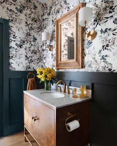 a bathroom with floral wallpaper and gold accents