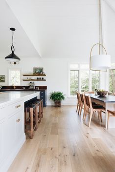 an open kitchen and dining room with hardwood floors, white walls, and ceiling lighting