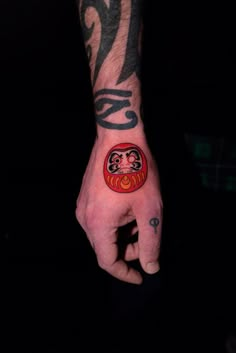 a hand with a red and black tattoo on it