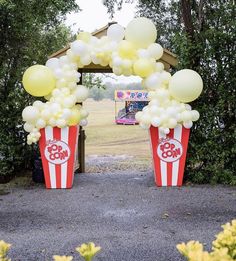 two popcorn buckets with balloons in the shape of numbers on them and an arch over them