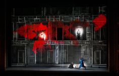 two people standing on stage in front of a building with red paint all over it