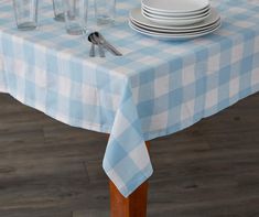 a blue and white checkered table cloth on a dining room table set with dishes