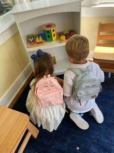 two children sitting on the floor with backpacks