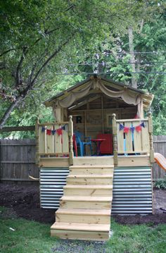 a small wooden structure with stairs leading up to it and a slide in the background