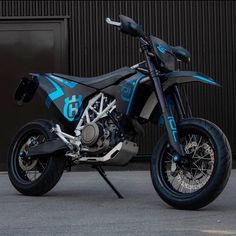 a blue and black dirt bike parked in front of a building with it's seat up