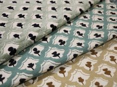 three different colored fabrics with black and white designs on them, one is green and the other is brown