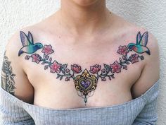 a woman's chest with two birds and flowers on it, all around her