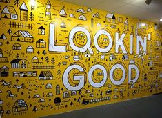 a yellow wall painted with black and white doodles that says lookin'good