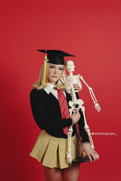 a woman in a skirt holding a skeleton and wearing a graduation cap with her hands behind her head