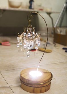 a small wooden stand with a chandelier on it's end and some beads hanging from the top