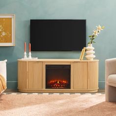 a living room with a fireplace and television on the wall, in front of a blue wall