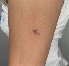 a small star tattoo on the back of a woman's thigh, it appears to be an astro sign