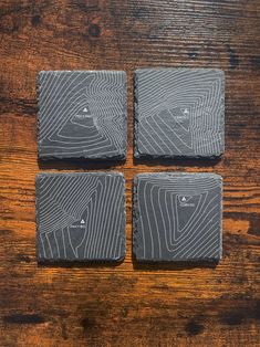 four square coasters on top of a wooden table with woodgrain patterning