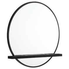 a round mirror sitting on top of a black shelf