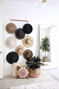 hats are hanging on the wall in front of a mirror and potted plant next to it