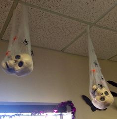 two stuffed panda bears hanging upside down from the ceiling in a room with white walls