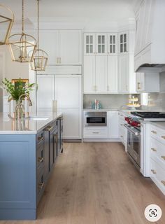 a large kitchen with white cabinets and blue island counter tops, gold accents on the doors