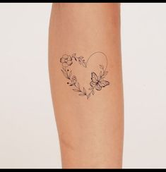 a woman's arm with a tattoo on it that has flowers and butterflies in the shape of a heart