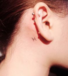 a woman's ear with a small cross tattoo on it