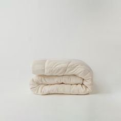 two blankets folded on top of each other in front of a white wall and floor