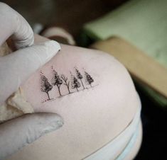 a woman's back with trees tattoo on her left side ribcage,