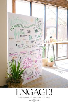 a large white sign sitting in front of a window next to a potted plant